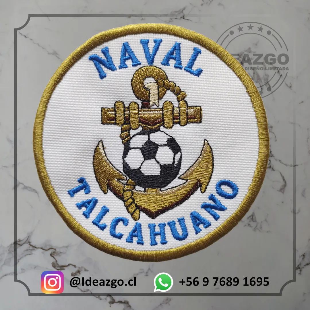 Parche bordado con texto que dice Naval Talcahuano color celeste un ancla con colores bronce y cafe, al medio de esta tiene un balón de futbol, el color de fondo es blanco y el borde del parche es color bronce
